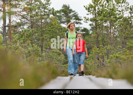 Madre e figlia camminando sul listone vie in foresta Foto Stock