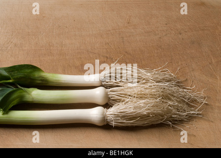 Tre i porri disposta orizzontalmente su di un tagliere di legno Foto Stock