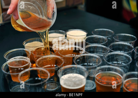 Versare la birra da pinta di vetro in piccoli bicchieri di campionamento Foto Stock