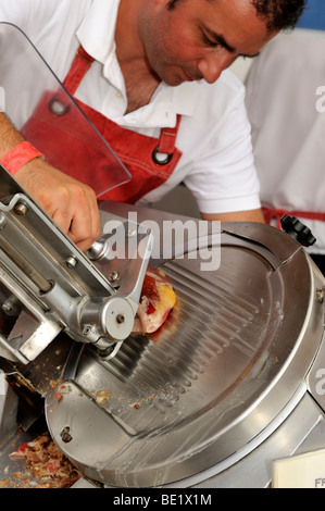 Macellaio per affettare il Prosciutto Prosciutto di Parma sulla macchina affettatrice Foto Stock