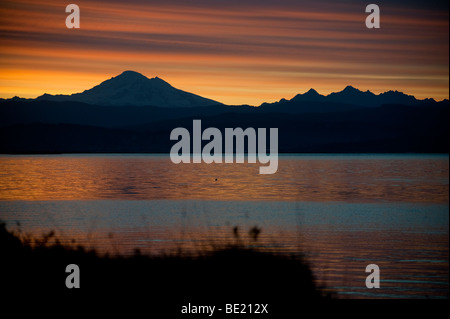 Tramonto su Mt. Baker e il 'Sisters'. Guardando oltre Bellingham Bay e la città di Bellingham nel nord-ovest del Pacifico, Stati Uniti d'America. Foto Stock