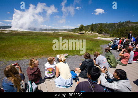 Guardare la gente geyser Old Faithful presso il Parco Nazionale di Yellowstone, Wyoming Foto Stock