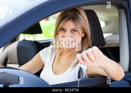 Giovane uomo seduto all'interno dell'auto che mostra i tasti alla nuova vettura Foto Stock