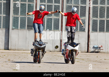 Due piloti stunt bike equitazione mentre in piedi sui serbatoi di gas Foto Stock