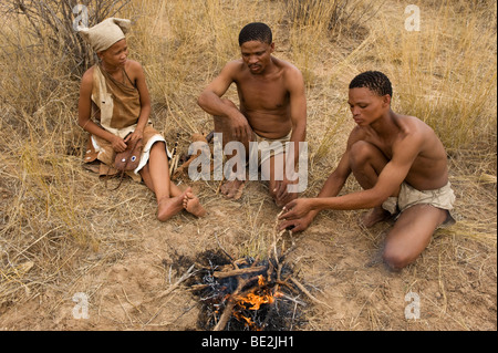 Naro bushman (SAN) seduto a un incendio, Central Kalahari, Botswana Foto Stock