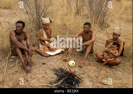 Naro bushman (SAN) seduto a un incendio, Central Kalahari, Botswana Foto Stock