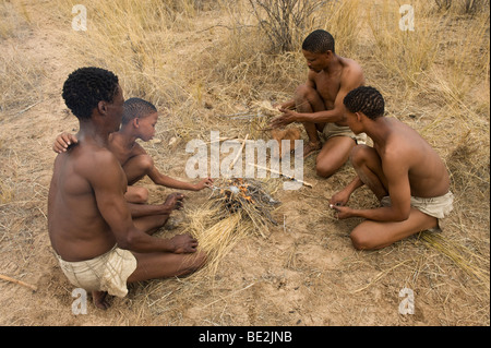 Naro bushman (SAN) seduto a un incendio, Central Kalahari, Botswana Foto Stock