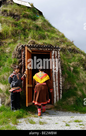 Donna che indossa il costume tradizionale del popolo Sami nella parte anteriore della sua terra coperta lodge, Hammerfest, Norvegia, Scandinavia, Foto Stock