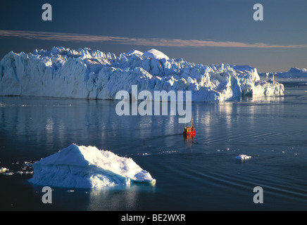 Barca da gamberetti nella parte anteriore di iceberg nel ghiaccio Kangia Fjord, Sito Patrimonio Mondiale dell'UNESCO, Ilulissat Foto Stock