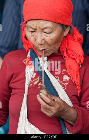 Hani donna tribale di fumare un tubo al mercato Menghun in Yunnan, Cina Foto Stock