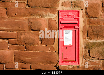 Un rosso postbox impostato in una parete di pietra arenaria Foto Stock