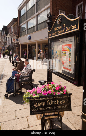 Regno Unito, Inghilterra, Staffordshire, Stafford, la piazza del mercato di acquirenti rilassante sul banco di prova nella luce del sole Foto Stock