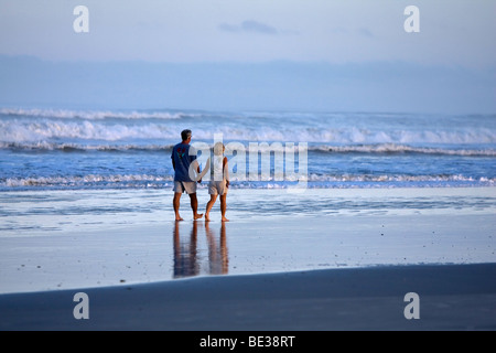 Giovane passeggiate mano nella mano mentre un uragano è al largo della costa atlantica. Foto Stock