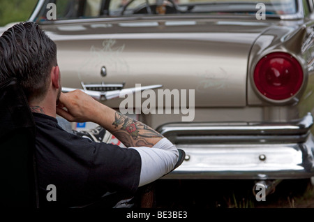 Uomo seduto di fronte alla parte posteriore della sua auto d'epoca Foto Stock