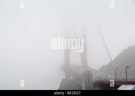 Golden Gate Bridge il traffico parzialmente oscurato da Fog San Francisco California // SAN FRANCISCO, California, Stati Uniti - il Golden Gate Bridge, con il traffico visibile sul ponte, è parzialmente oscurato dalla fitta nebbia mentre si estende attraverso la baia di San Francisco. Questo iconico ponte sospeso, completato nel 1937, è celebrato per il suo caratteristico colore arancione internazionale e il design Art Deco. È considerata una significativa meraviglia ingegneristica del XX secolo. L'estensione principale del ponte misura 1.280 metri (4.200 piedi) e la sua lunghezza totale è di 2.737 metri (8.981 piedi). Collega la città di Foto Stock