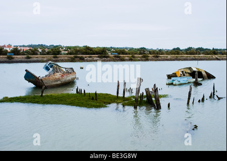 Sunken barche di laici in un fiume di alimentazione del golfo di Biscaglia sull'isola Ile de Noirmoutier, Vendee, Francia. Foto Stock