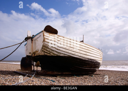 Un legno bianco pesca barca tirata su di una spiaggia di ciottoli Foto Stock