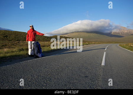 Autostoppista femmina sul vuoto strada di montagna, Isola di Skye in Scozia Foto Stock