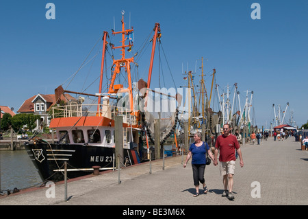 I turisti accanto alla flotta di pescherecci per gamberetti nel porto Neuharlingersiel, Mare del Nord Frisia orientale, Bassa Sassonia, Germania, Europa Foto Stock