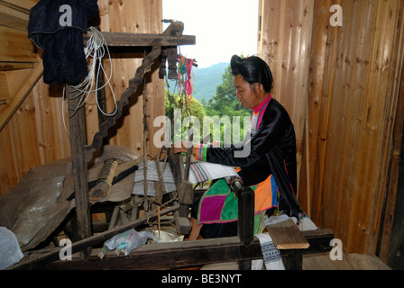Telaio di un Basha donna in un abito di battuto in cotone nero in una casa di legno della minoranza Basha, Basha, Guizhou, Cina e Asia Foto Stock