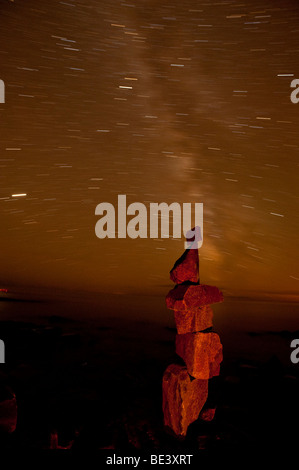 Stelle lasciano scie nel cielo dietro il rock CAIRN Foto Stock