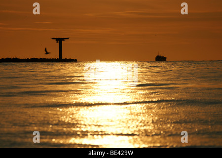 Tramonto Tramonto su Hoek van Holland dyke dam colorato arancione sera calmo mare orizzonte lontano la riflessione della luce riflessa Foto Stock