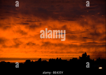 Nuvole lenticolari mostrato contro un profondo rosso e arancione tramonto infuocato guardare quasi come alien i visitatori nel cielo Foto Stock