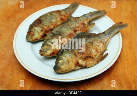 Pesce fritto carassio nella piastra sulla tavola di legno