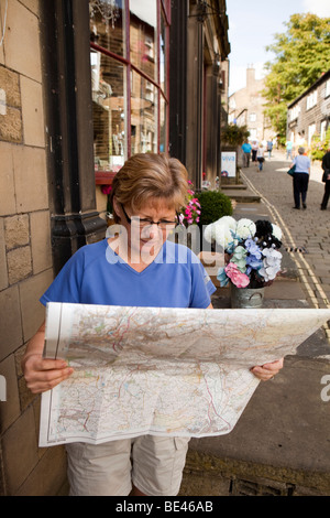 Regno Unito, Inghilterra, Yorkshire, Haworth, Main Street, femmina walker guardando Ordnance Survey Map Foto Stock