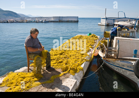 Rammendo reti sul lato della banchina nel piccolo porto di Aghios Nikolaos, nella parte esterna di Mani, sud del Peloponneso, della Grecia. Foto Stock