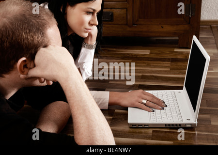 Coppia giovane disteso di fronte a un computer portatile insieme Foto Stock