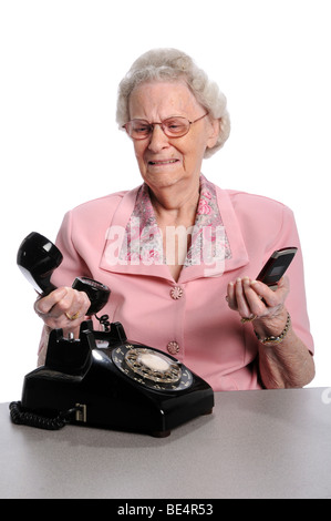 Donna anziana holding vintage e telefono cellulare isolato su sfondo bianco Foto Stock