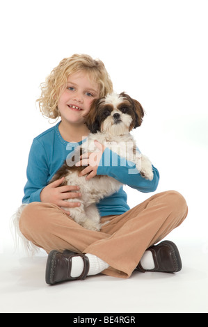 A sette anni di ragazza con il suo Shih Tzu cane, sorridente e guardando il visualizzatore. Foto Stock