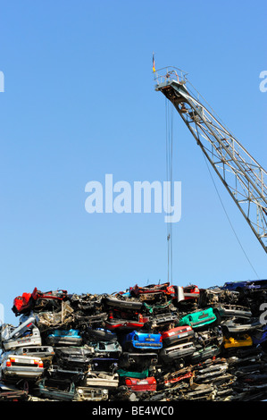 Le auto vecchie e una gru di carico su un junkyard Foto Stock