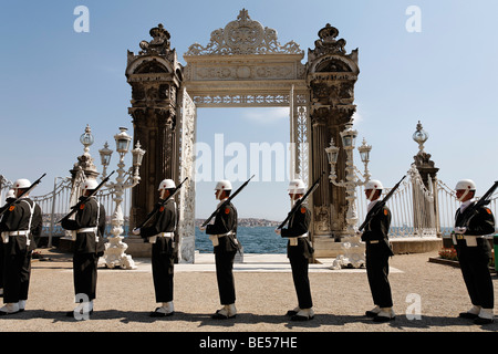 Montagna di guardia di fronte al cancello principale sul Bosforo a riva, Palazzo Dolmabahce, Besiktas, Istanbul, Turchia Foto Stock