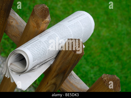 Giornale arrotolato tra due fenceposts Foto Stock