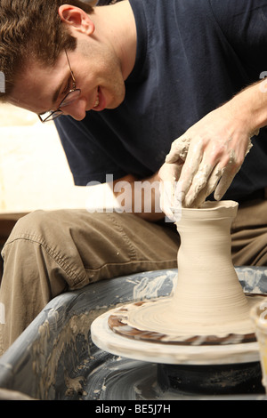 Giovane uomo rendendo la pentola con ruota in ceramica Foto Stock