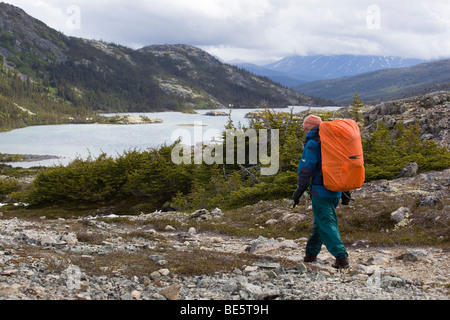 Escursionista femmina, backpacker passeggiate nel paesaggio alpino, Lago Profondo dietro, Chilkoot Trail, Chilkoot Pass, Yukon Territory, inglese britannico Foto Stock