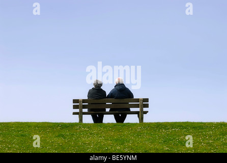 Coppia di anziani seduti su una panchina su una diga Foto Stock