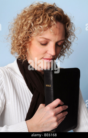 Giovane donna orante tenendo una Bibbia Foto Stock