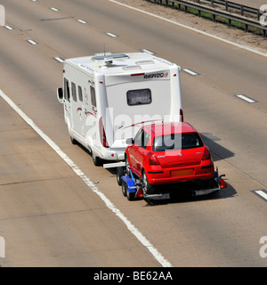 M25 Autostrada camper van oscurate targa traino di una Suzuki Swift auto Foto Stock