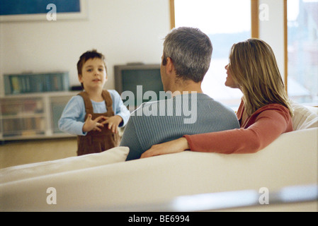 Little Boy a parlare con i suoi genitori seduti sul divano Foto Stock
