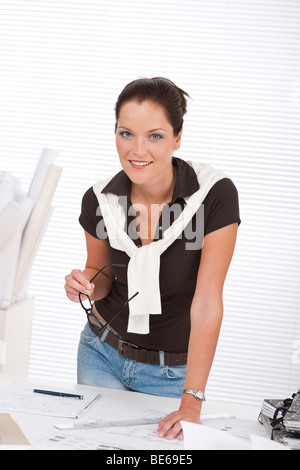 Sorridente architetto di successo donna con piani in ufficio Foto Stock