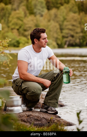 Un uomo l'infiltrazione di acqua su un viaggio di campeggio nella foresta Foto Stock