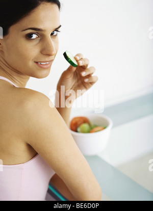 Giovane donna mangiare fette di verdure crude Foto Stock