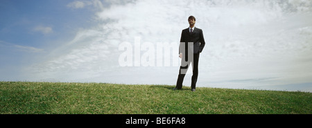 Imprenditore nel campo erboso con la mano in tasca Foto Stock