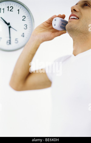 Uomo al telefono chiamata, orologio in background Foto Stock