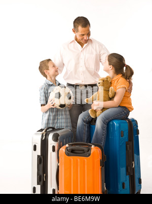 Padre di due figli, circondato da valigie Foto Stock