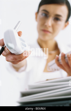 Donna tenendo fuori un telefono cordless, prospettiva personale Foto Stock