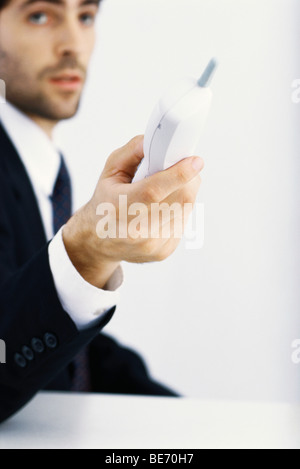 Imprenditore tenendo fuori del telefono cordless Foto Stock